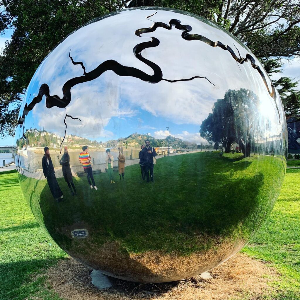 Spherical park mirror with a dark squiggle across the top and Will et all reflected in it