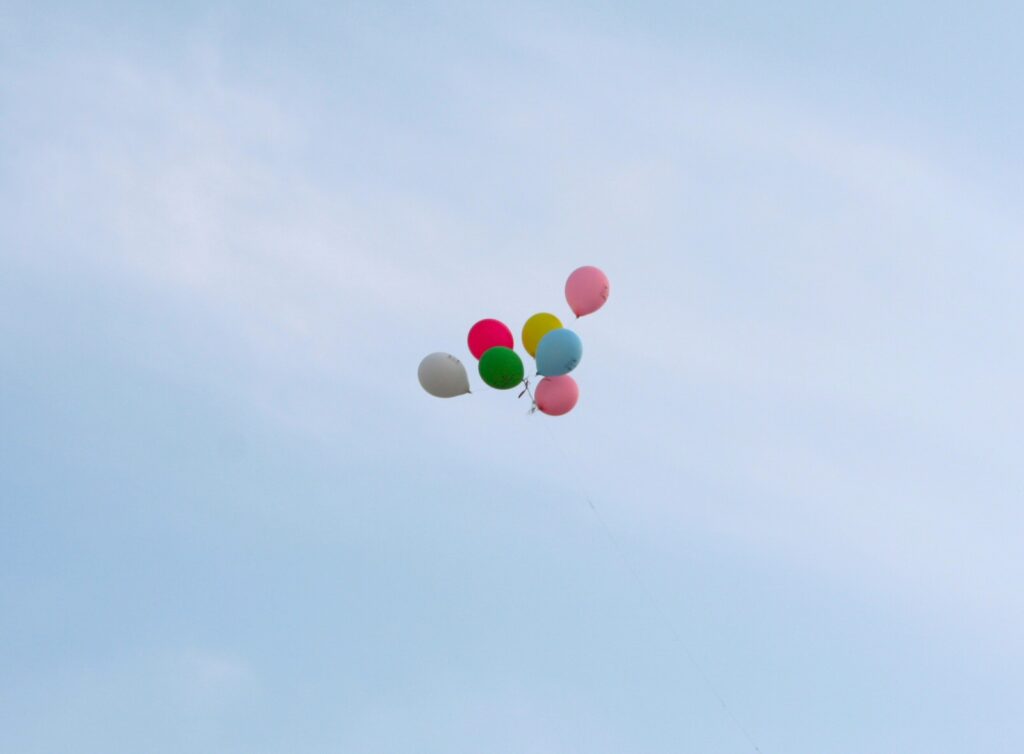 A cluster of balloons escaping into the sky.