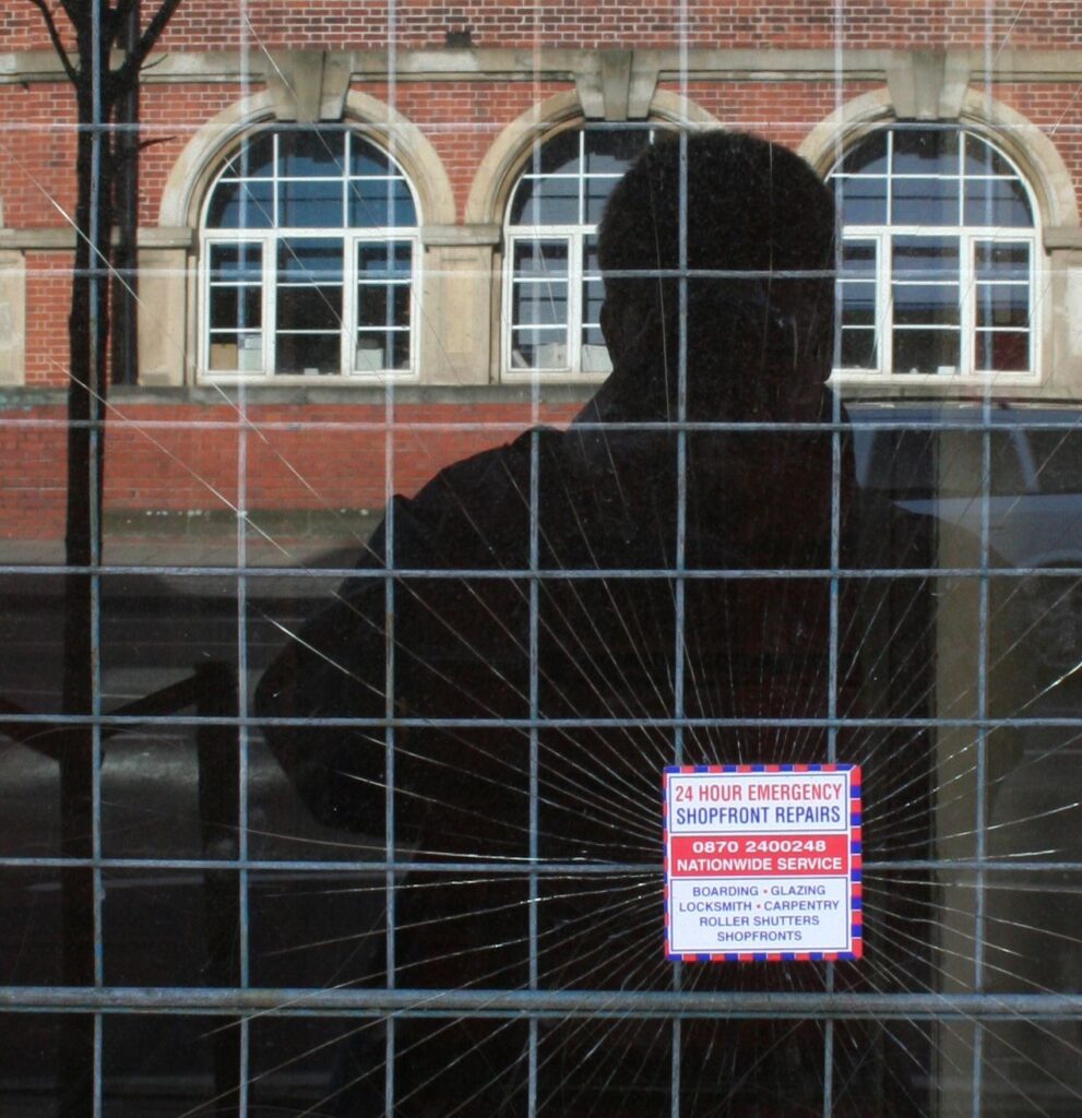 Self-portrait in shadow, reflected in shattered glass, somewhere on a Tube Walk in London.
