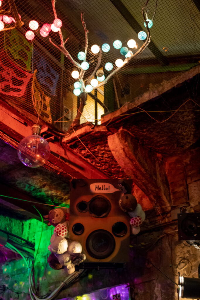 Lighted artwork from the ruin pub at Szimpla Kert, in Budapest, with an old speaker box facing the lens and a speech bubble above it saying 
