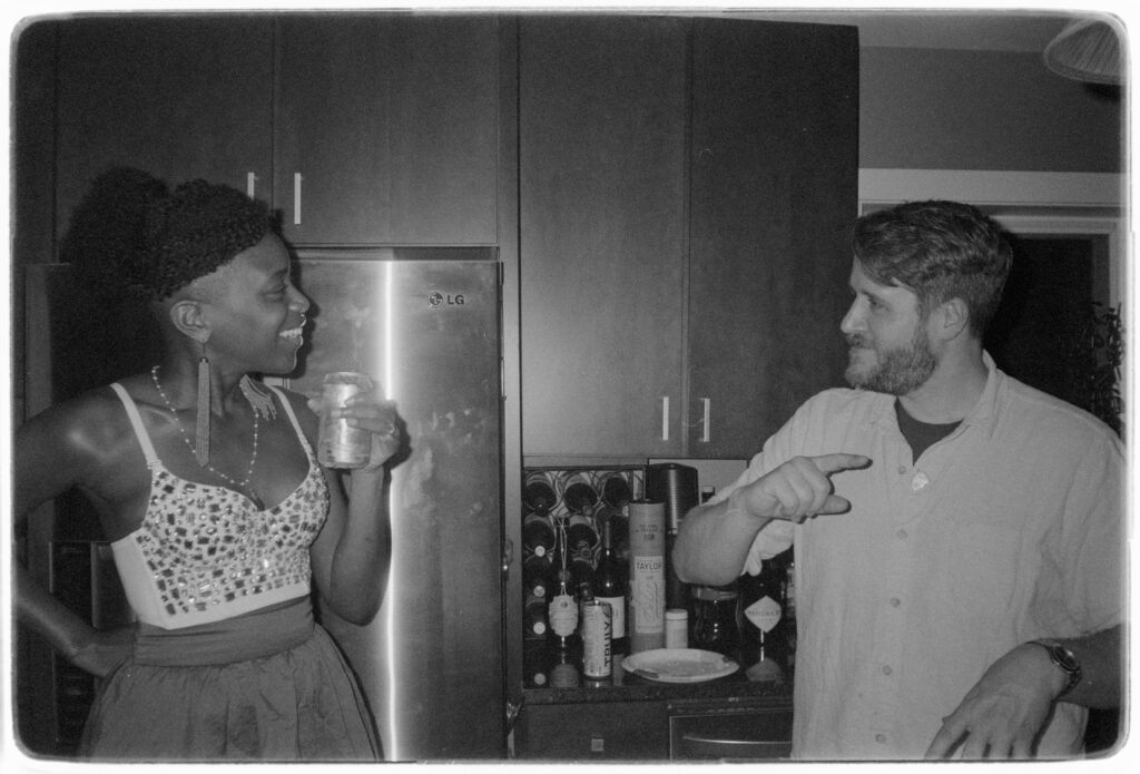 Ayo and Stephen, in a kitchen and monochrome, having a totally not posed conversation.