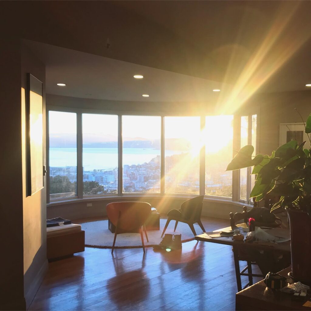 Lens flare through the panoramic windows of a living room with a view.