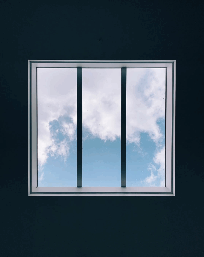 A skylight against a dark ceiling, with two vertical bars against bright clouds in a blue sky. This might also be James Turrell artwork, I'm not sure.